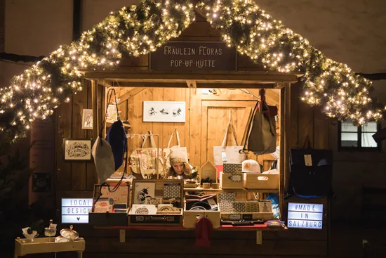 Christmas market stall with handmade gifts, tote bags and festive lights in Salzburg